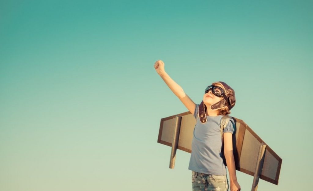 photo of a kid with airplane wings and helmet